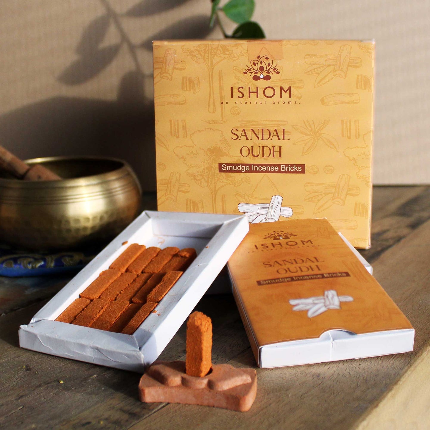 Pack of fifteen dark brown sandalwood incense bricks arranged next to a small round terracotta burner bowl.