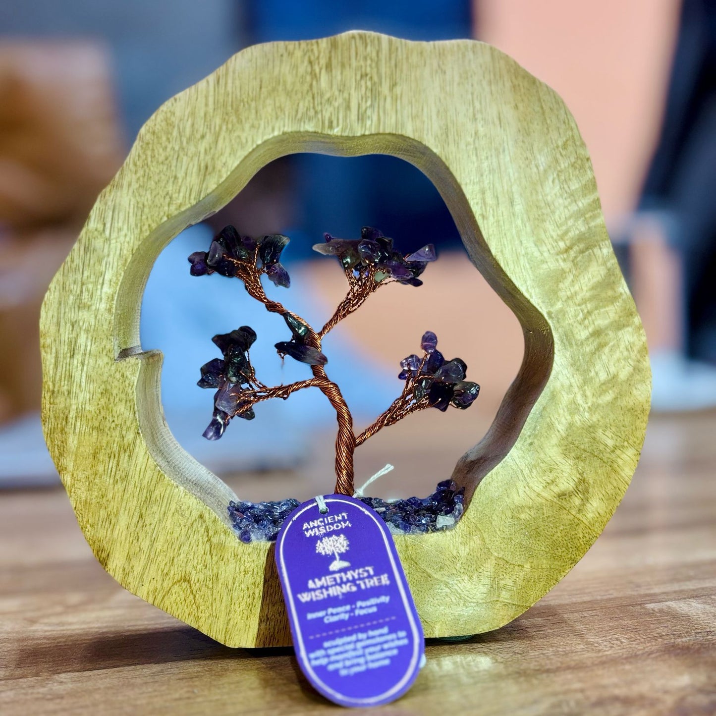 Handcrafted amethyst gemstone tree with sixty purple chipstones rooted inside a circular carved mango wood frame.