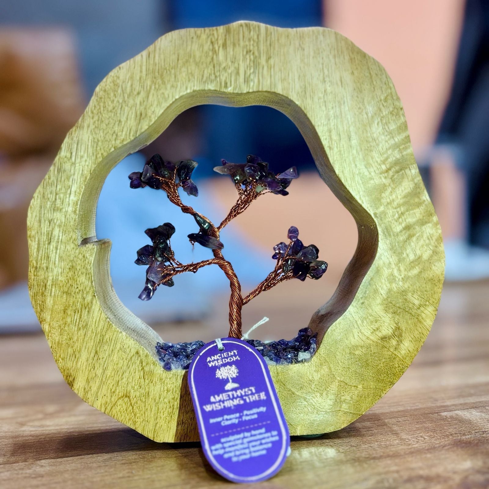 Handcrafted amethyst gemstone tree with sixty purple chipstones rooted inside a circular carved mango wood frame.