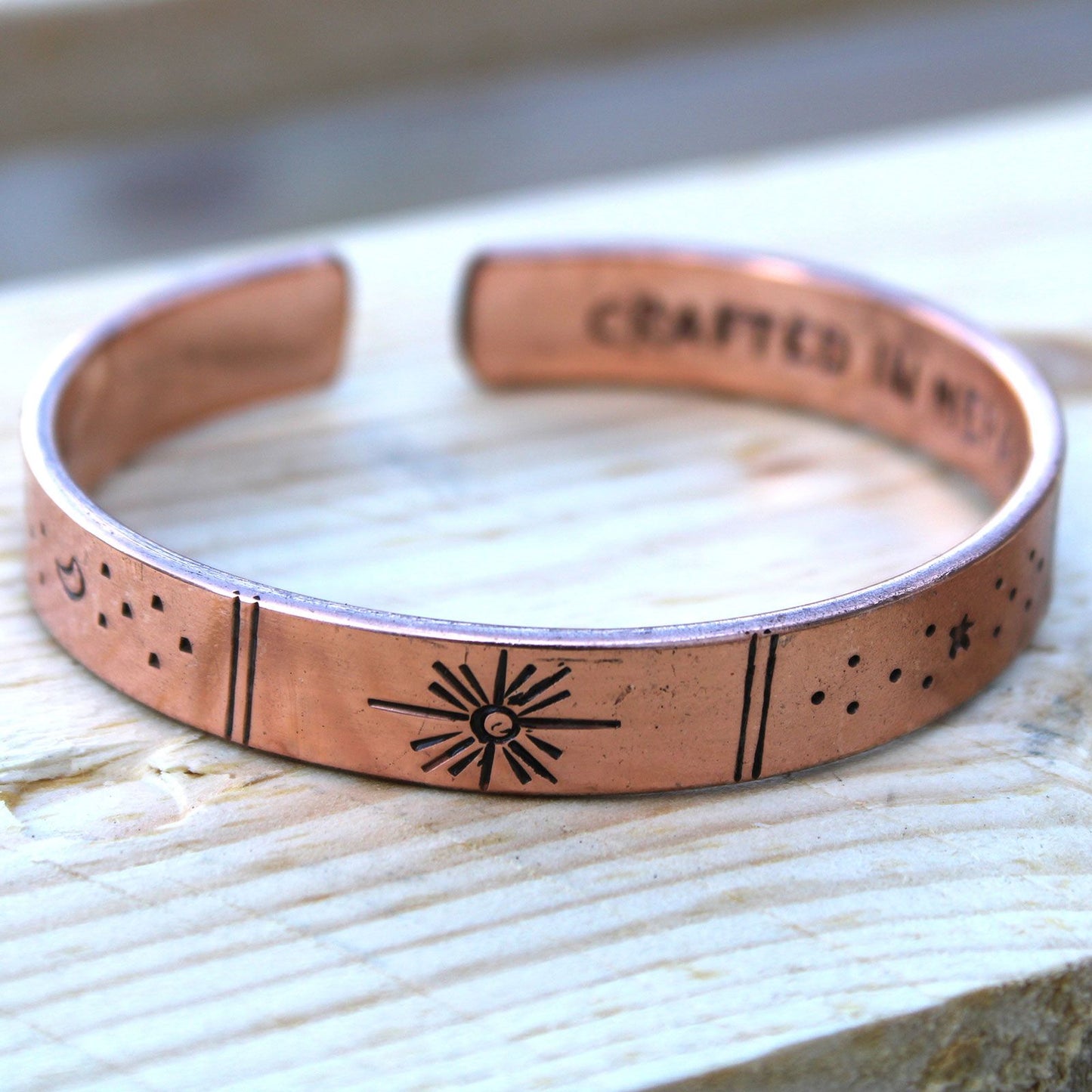 Handcrafted mixed metal adjustable cuff bracelet featuring etched celestial designs of stars and galaxies.