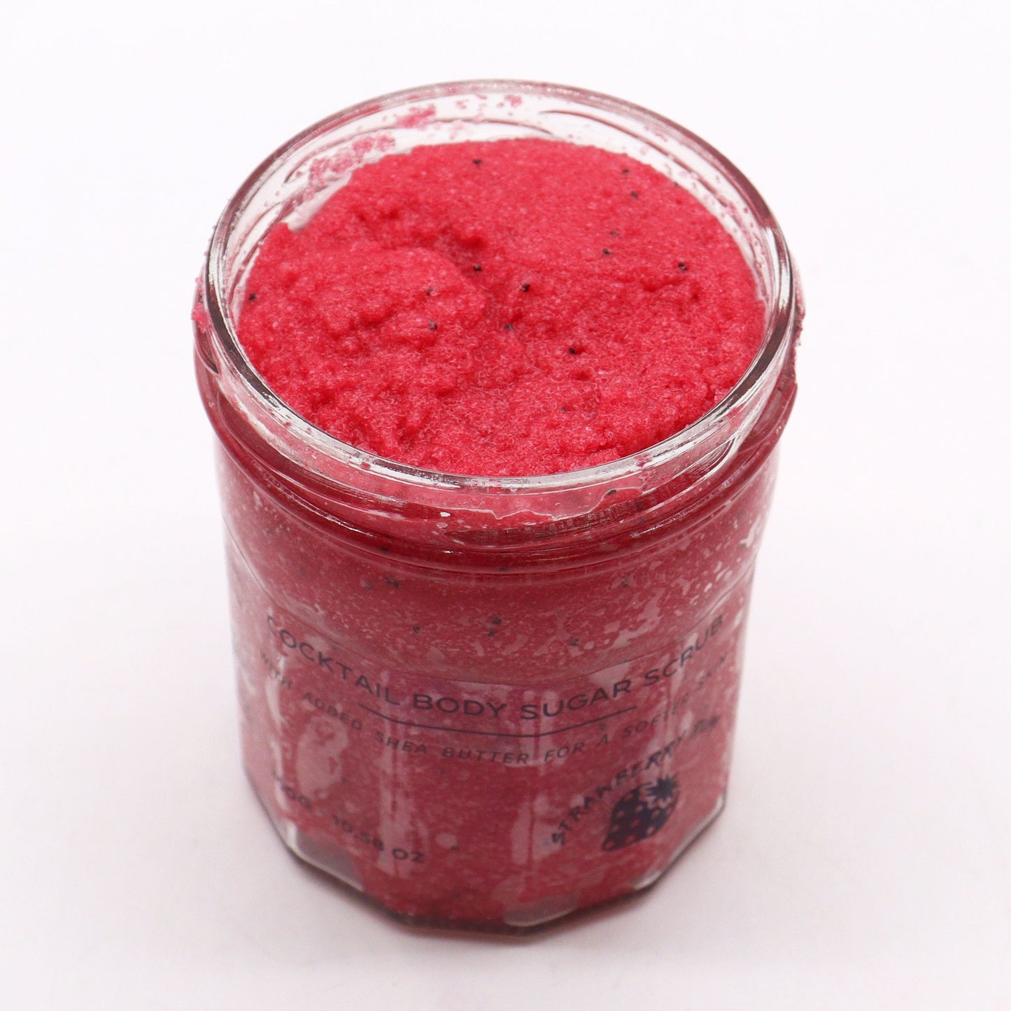 Close-up of textured pink sugar body scrub in a jar, showcasing a grainy exfoliating consistency.