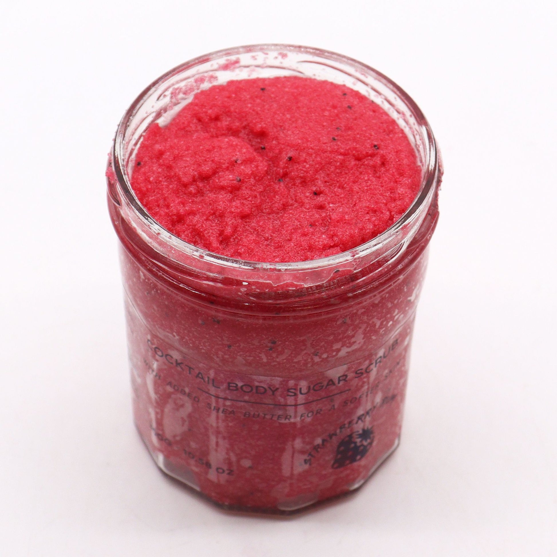 Close-up of textured pink sugar body scrub in a jar, showcasing a grainy exfoliating consistency.