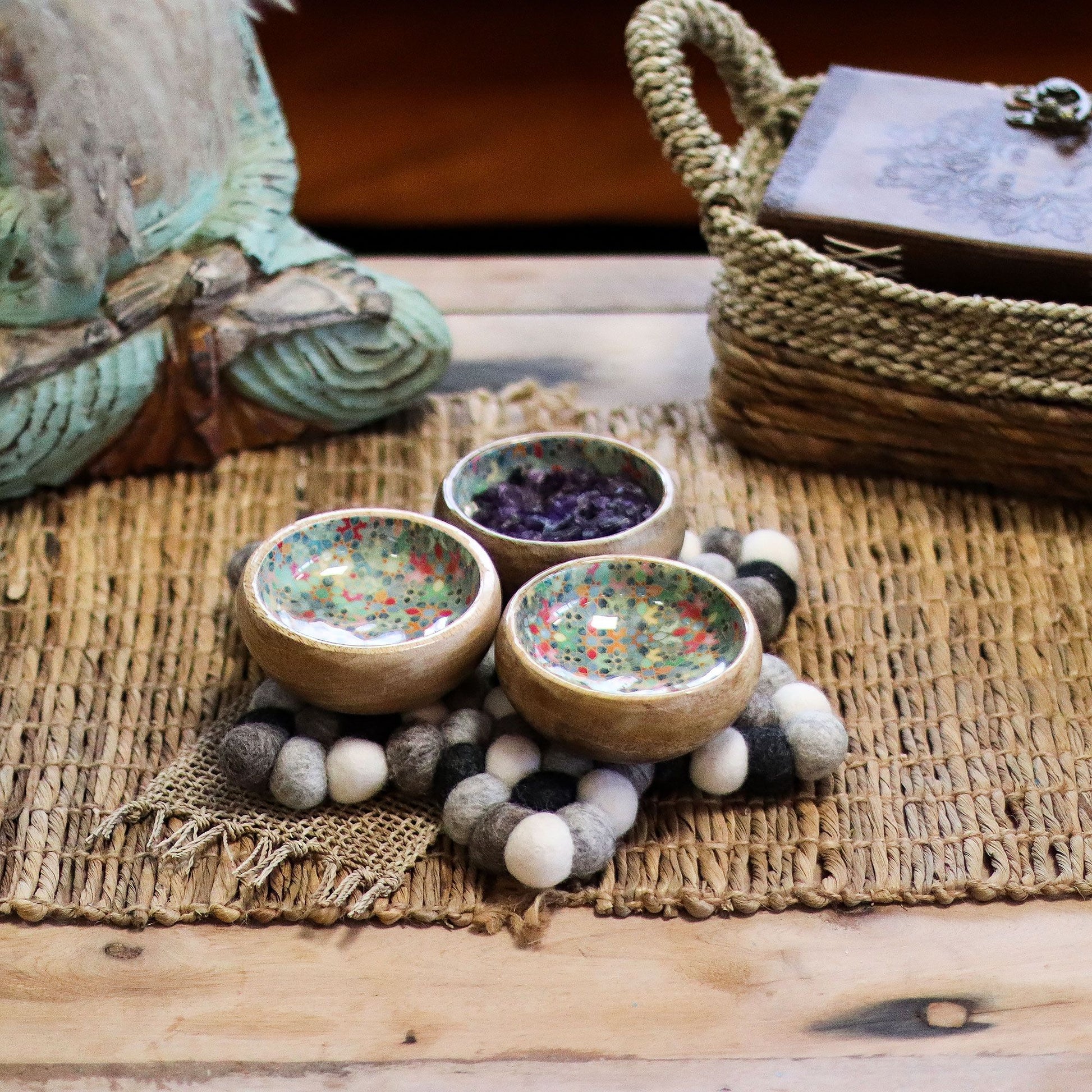 Round handmade centre mat featuring grey felt balls arranged in a star pattern for table protection.