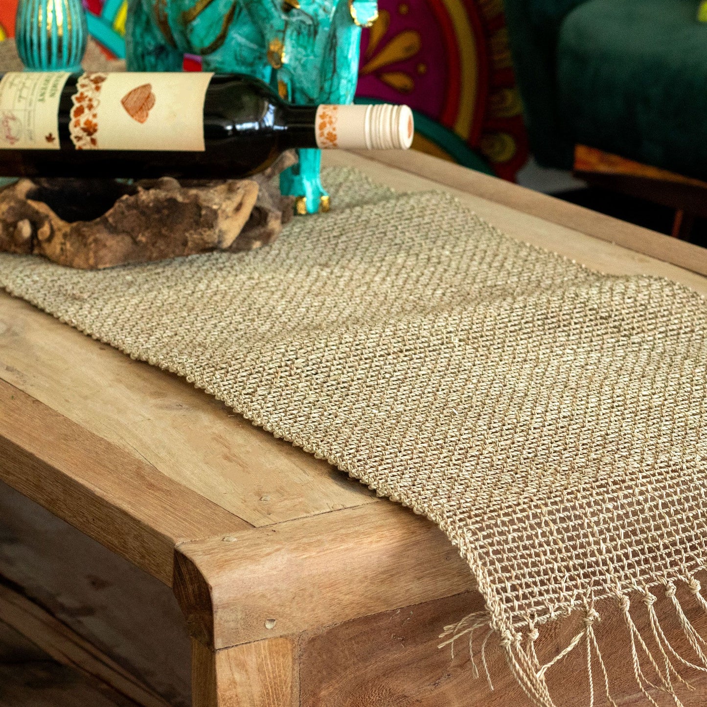 Handwoven natural seagrass table runner with delicate fringe detailing on a wooden surface.