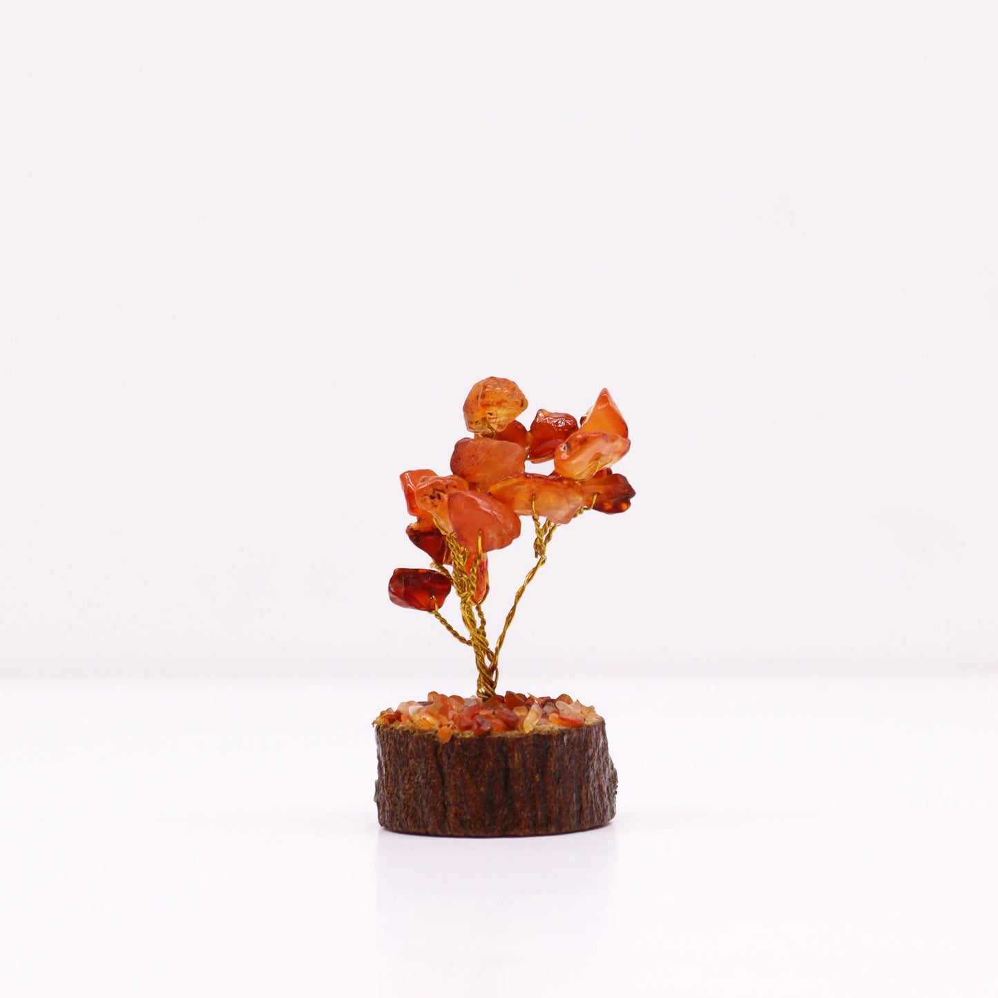Small carnelian crystal tree with orange gemstone leaves on a natural wood base.