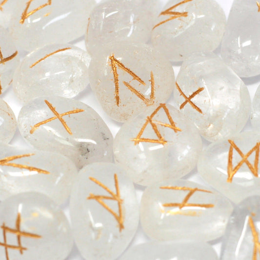 Set of clear crystal rune stones with engraved symbols laid out next to a small drawstring storage pouch.