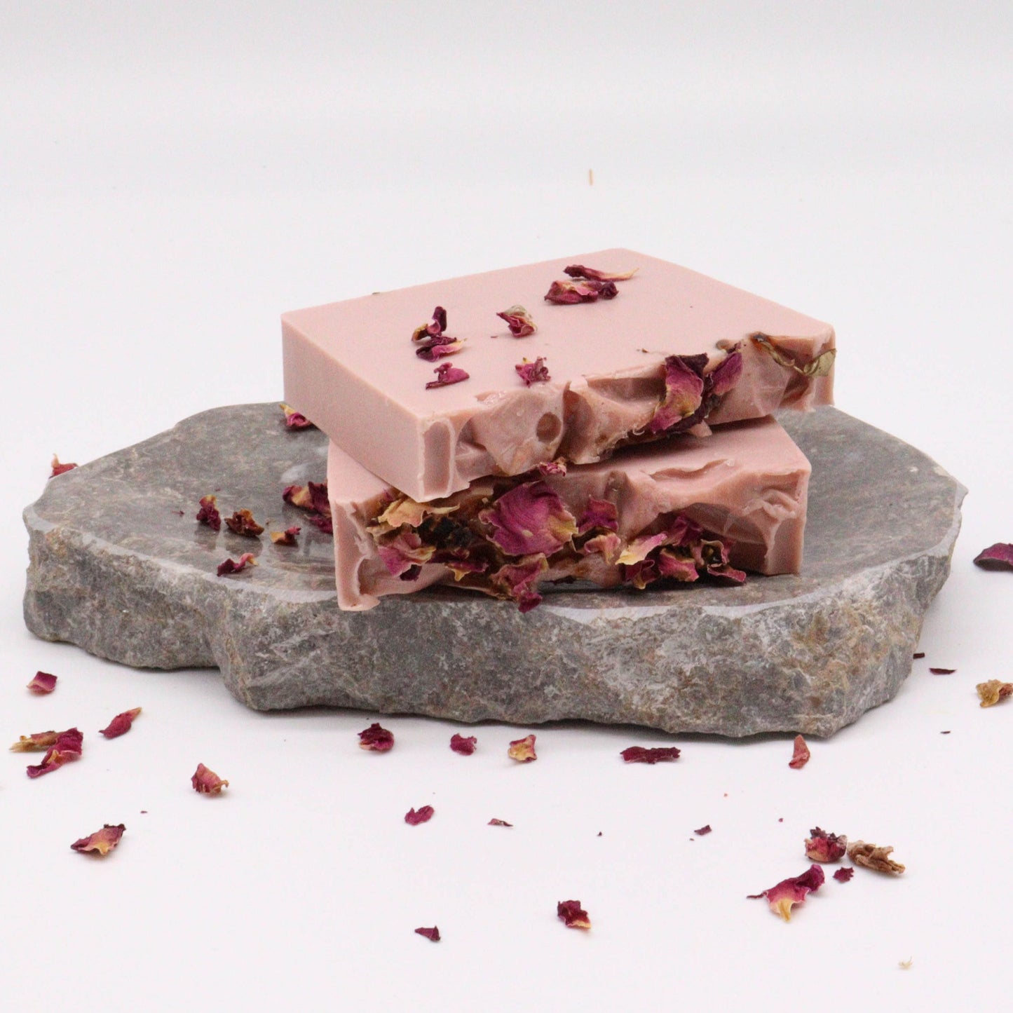 Hand-crafted pink and white soap bar with a textured top, showing delicate rose petal details.