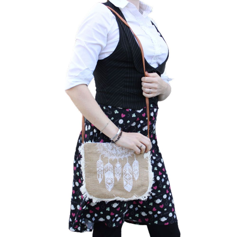 Soft jute shoulder bag featuring a dream catcher screen print, cotton fringe detail, and a long dark brown strap.