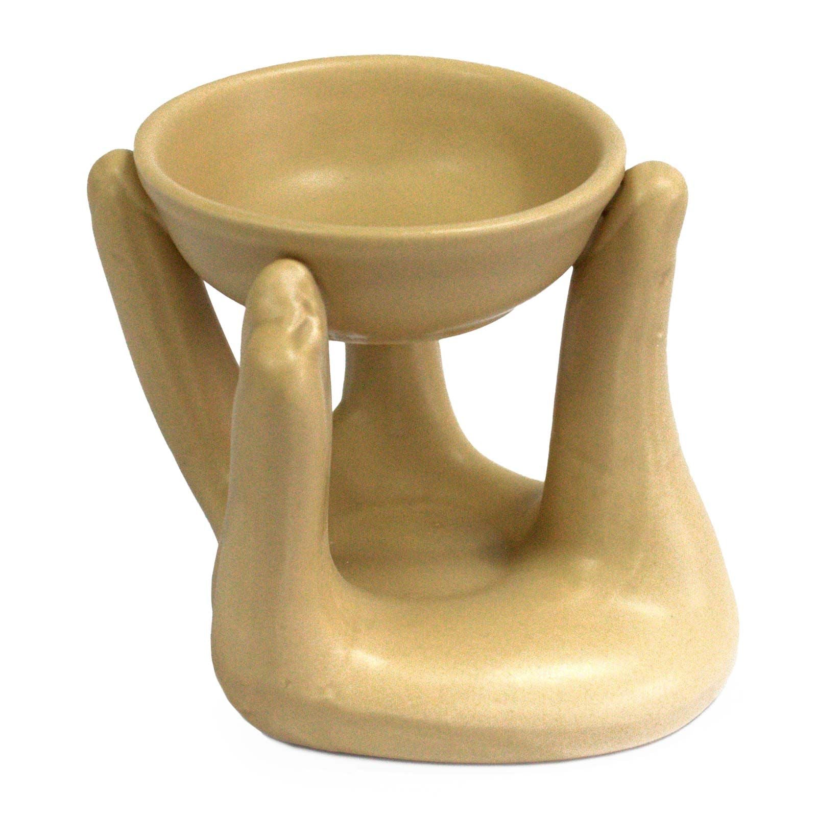 Minimalist tan-coloured ceramic oil burner shaped like two cupped hands holding a small glass dish for wax melts or oils.