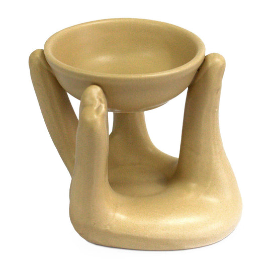 Minimalist tan-coloured ceramic oil burner shaped like two cupped hands holding a small glass dish for wax melts or oils.