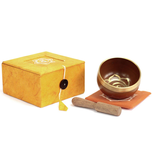 Handcrafted orange Tibetan singing bowl with sacral chakra symbols and a wooden striker.