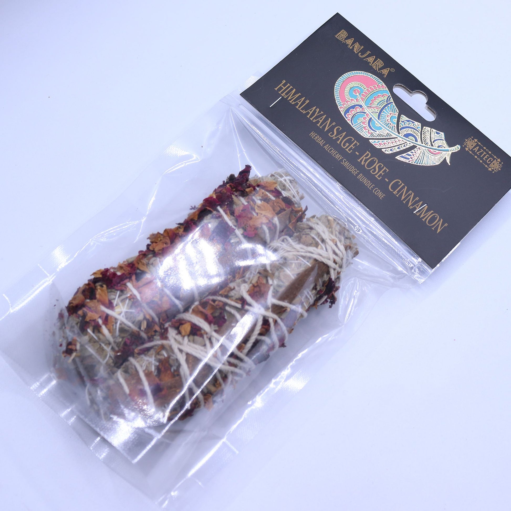 Handcrafted smudge stick bundle featuring dried green sage leaves, delicate pink rose petals, and a whole cinnamon stick.