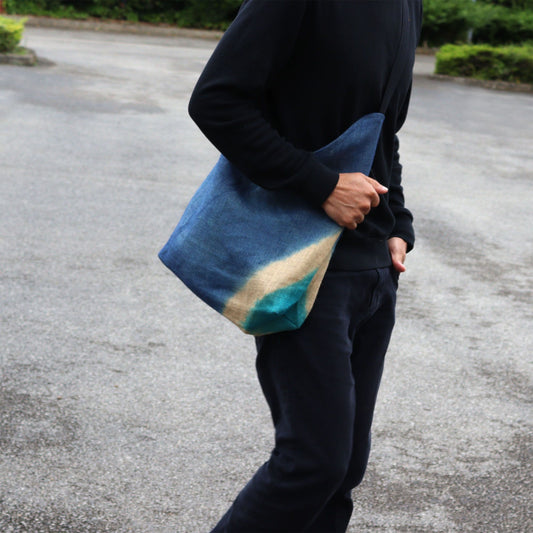 Denim blue textured shoulder tote bag crafted from a soft blend of jute and cotton with a minimalist aesthetic.