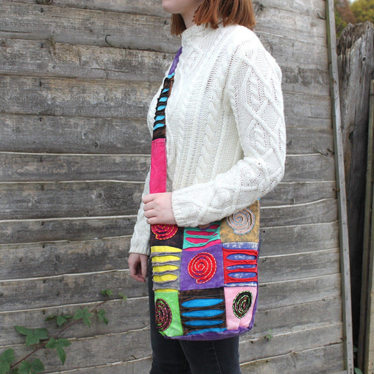 Vibrant purple ethnic sling bag featuring an embroidered spiral design and a comfortable long shoulder strap.