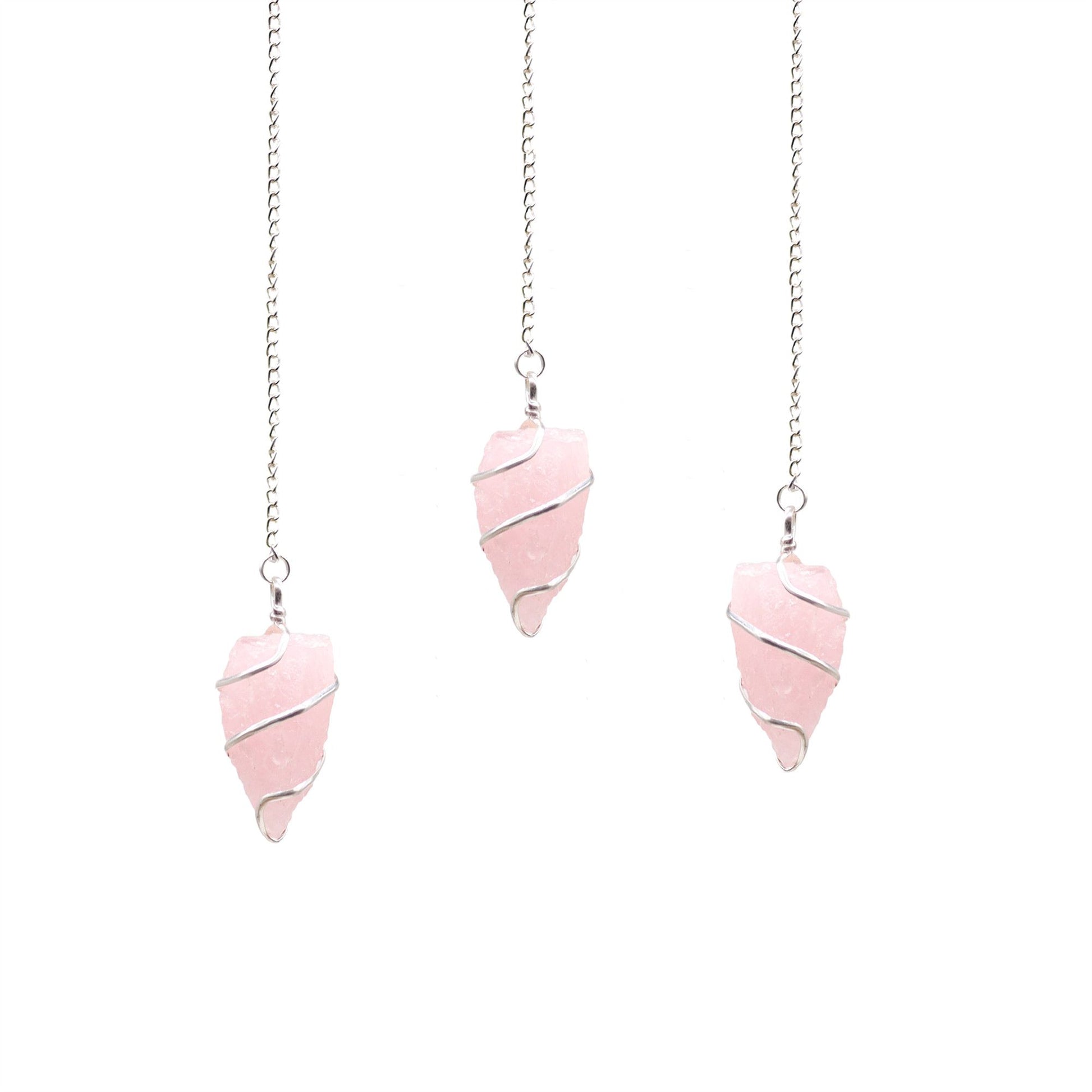 Uncut natural rose quartz gemstone pendulum with a delicate silver chain against a neutral background.
