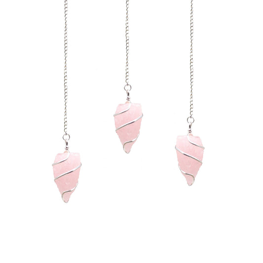 Uncut natural rose quartz gemstone pendulum with a delicate silver chain against a neutral background.