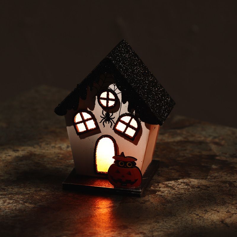 Intricately detailed miniature Halloween house featuring a spider web and spider with warm LED lights glowing from within.
