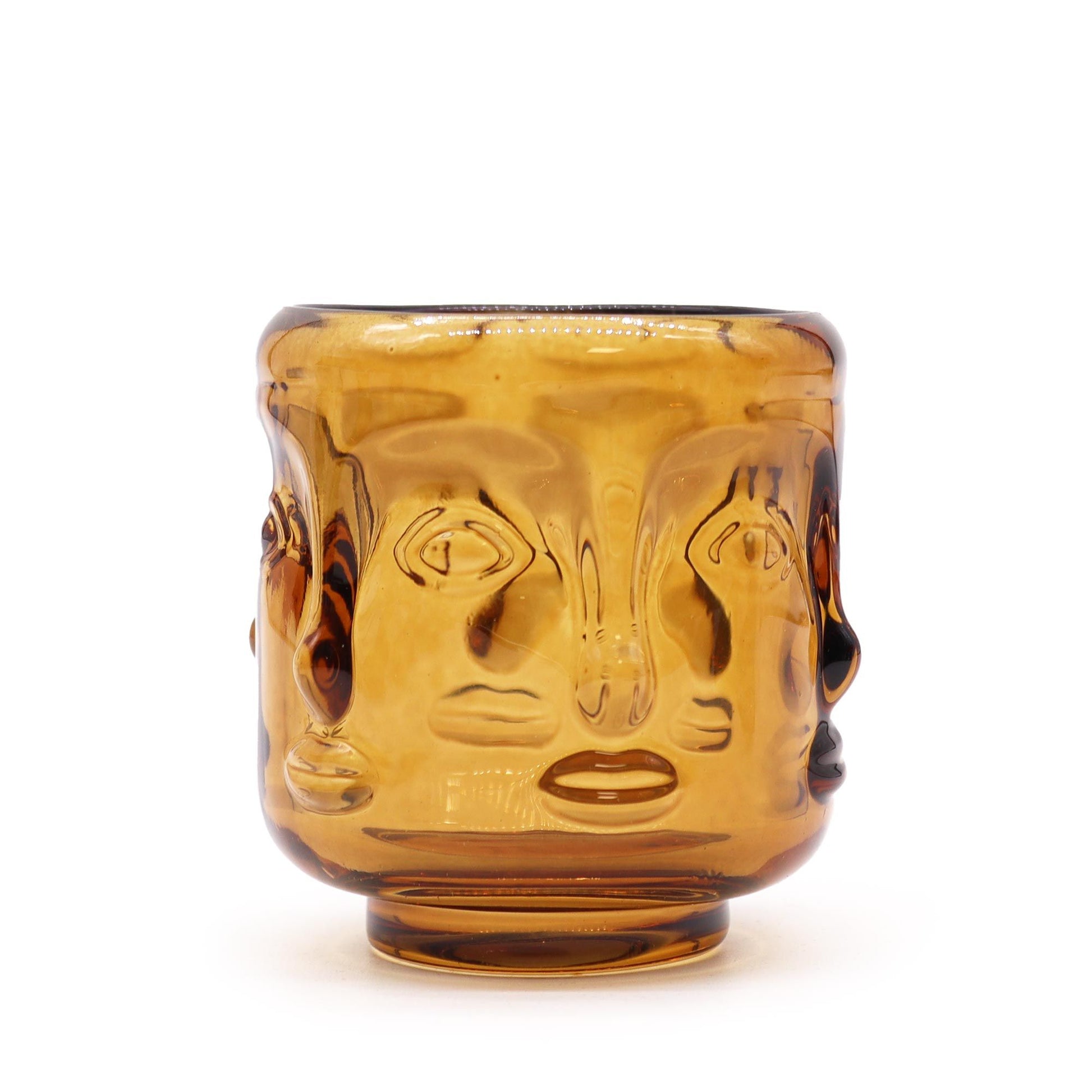 Antique amber glass candle jar featuring embossed Buddha faces and a decorative lid.