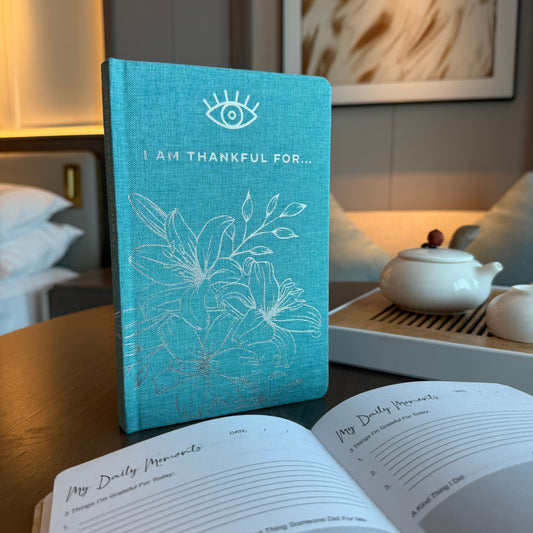 Blue textured hard cover gratitude journal with silver floral detailing and an elegant eye symbol.