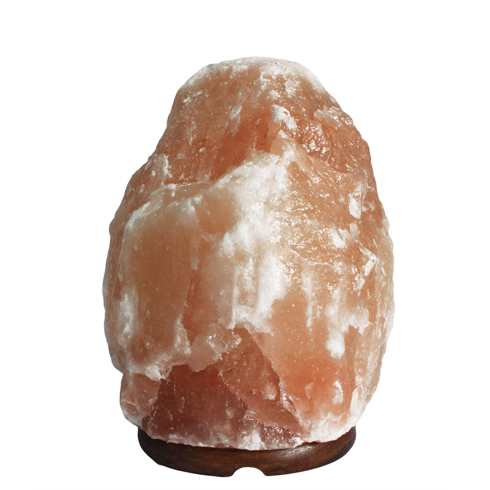 Large natural pink Himalayan salt lamp on a dark wooden base, emitting a warm orange glow in a peaceful room.