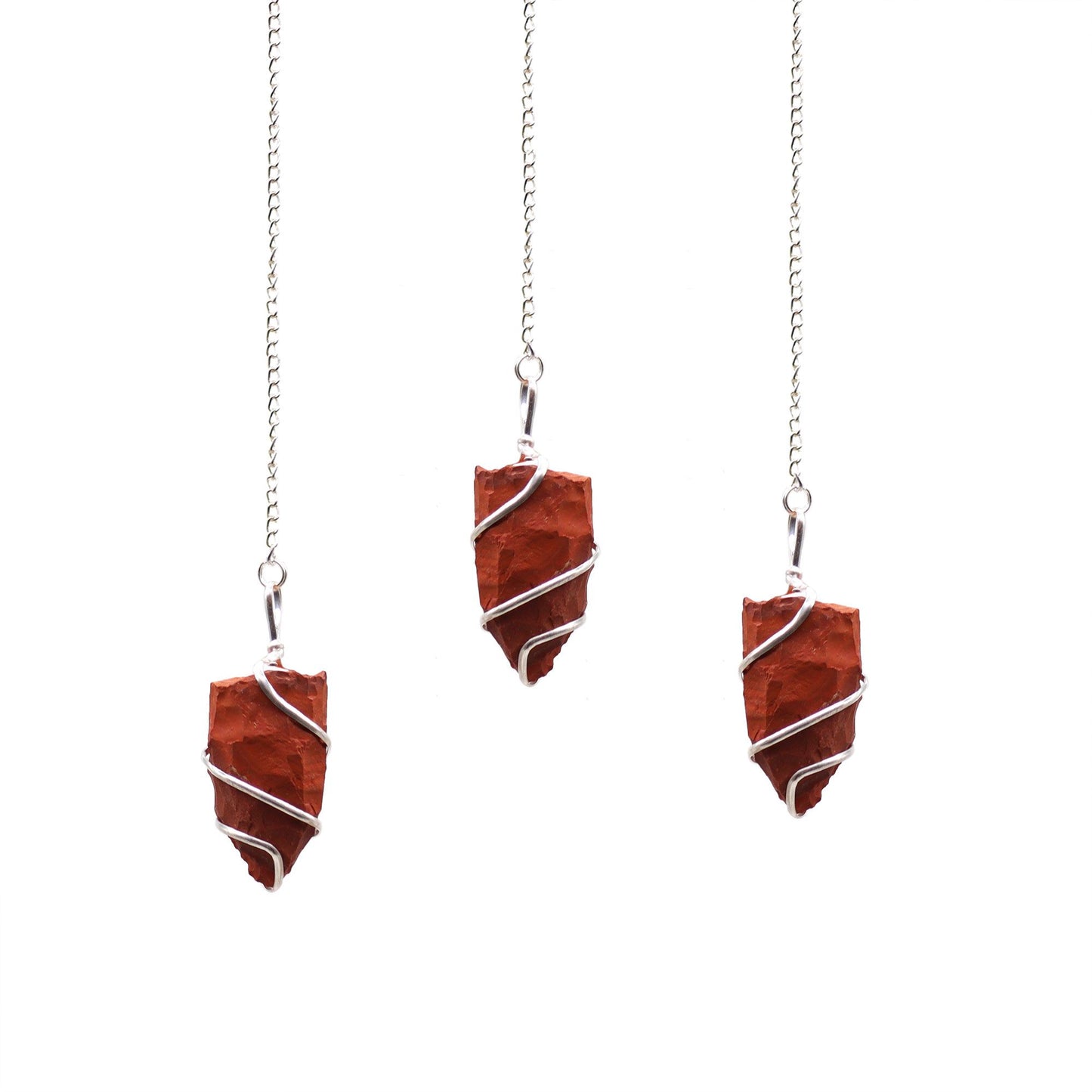 A natural unpolished red jasper gemstone pendulum attached to a delicate silver-tone chain for dowsing.