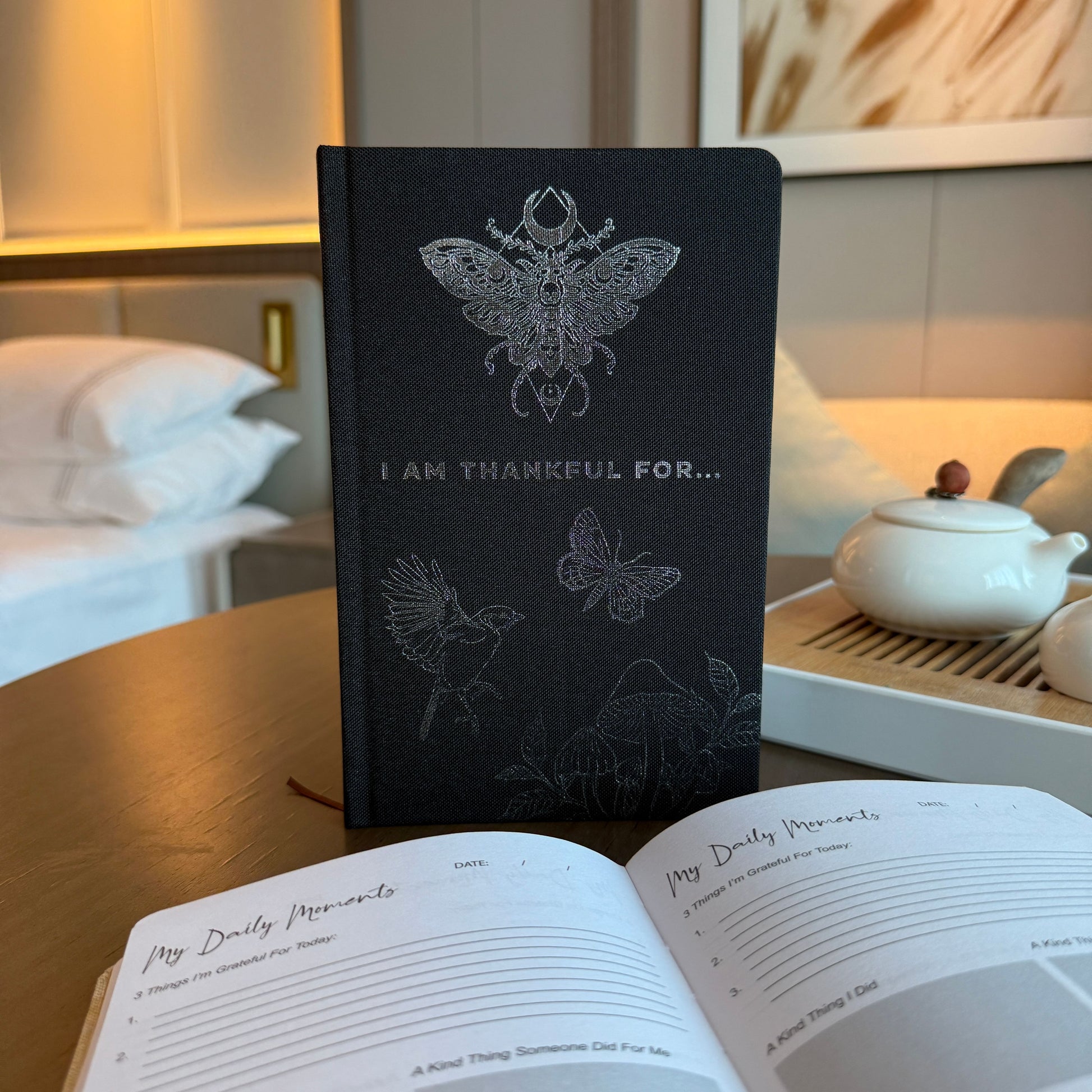 Hardback black gratitude journal with elegant silver lining and 'I Am Thankful For' text on the cover.