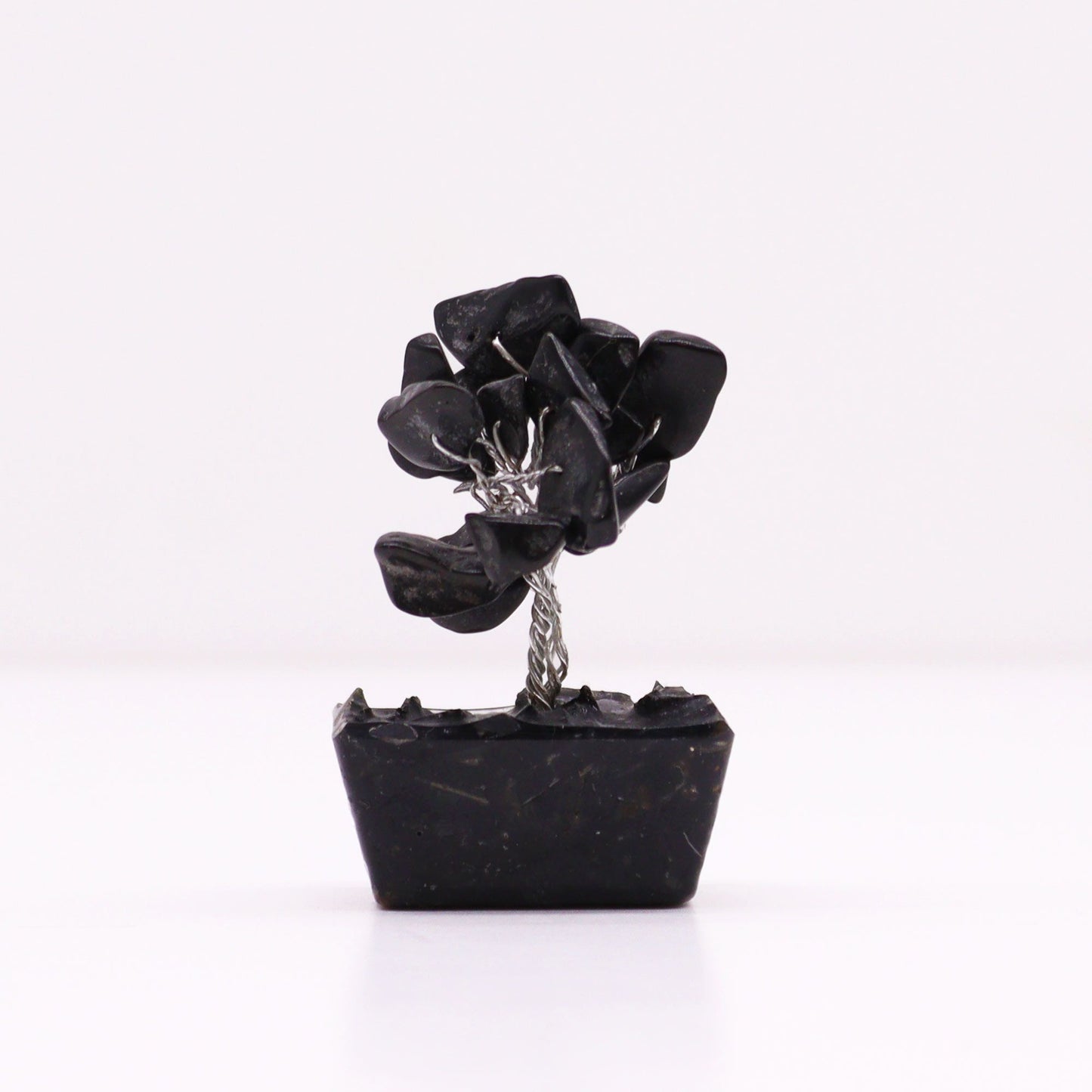 Miniature gemstone tree with black agate leaves on a decorative orgonite base.