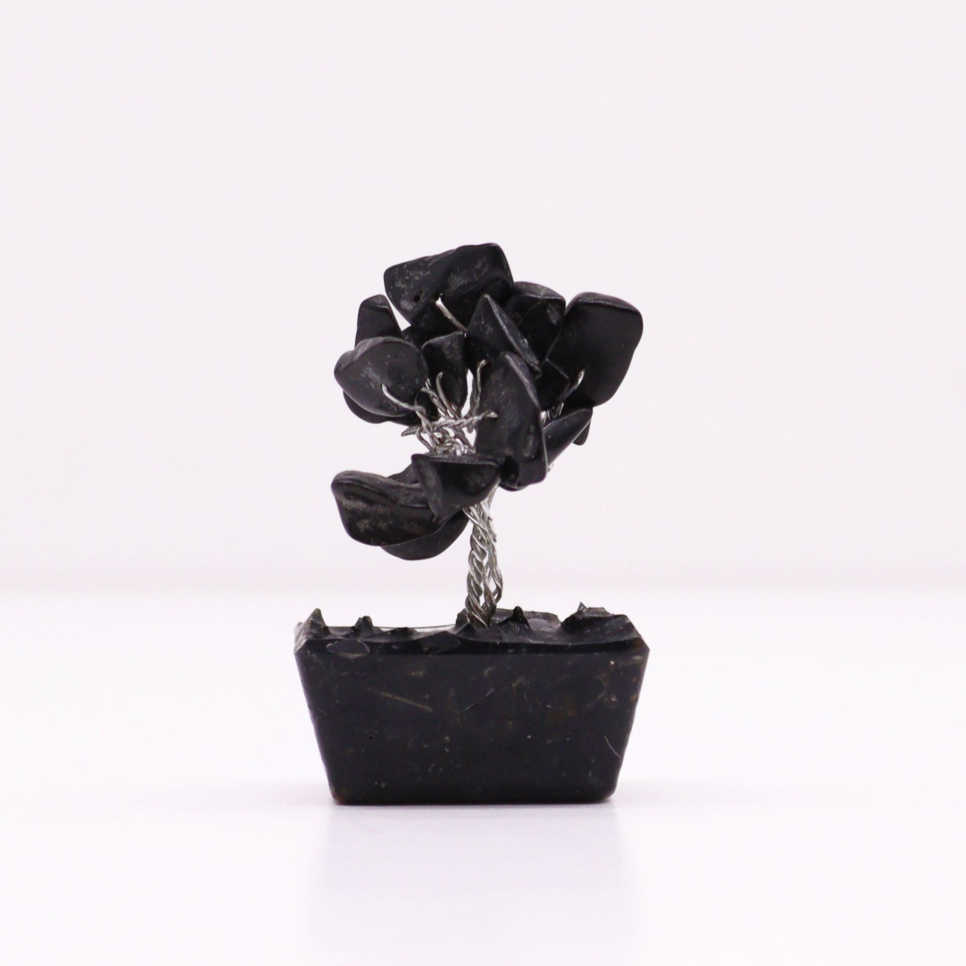 Miniature gemstone tree with black agate leaves on a decorative orgonite base.