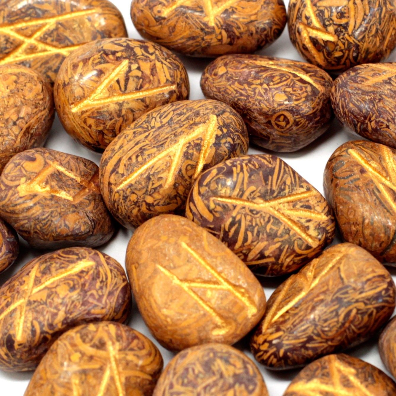Polished snake jasper rune stones with engraved symbols laid out next to a small drawstring storage pouch.