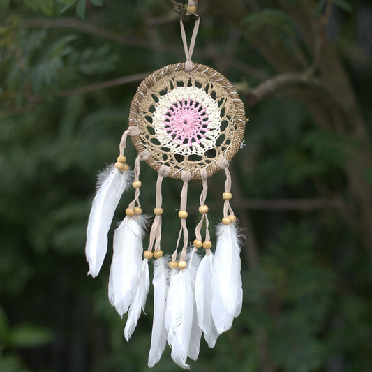 Delicate pastel pink macramé dream catcher with a woven web and hanging cotton tassels.