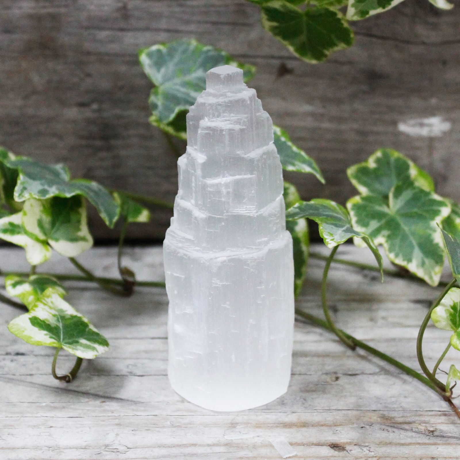 A 10cm tall natural selenite crystal tower with a translucent white finish and vertical striations.