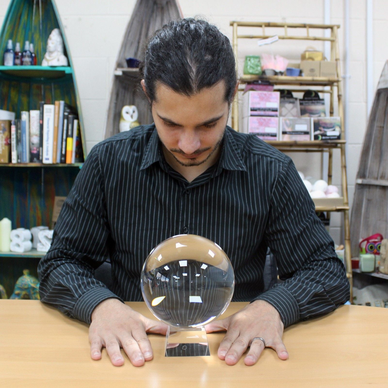 Large clear glass crystal ball resting on a minimalist wooden stand on a plain surface.