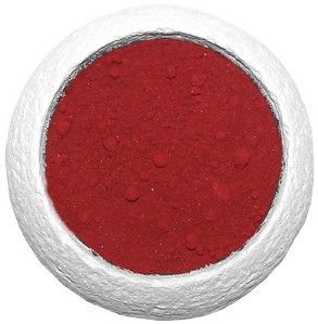 Fine deep red aromatic dragon's blood resin powder in a clear glass jar on a wooden surface.
