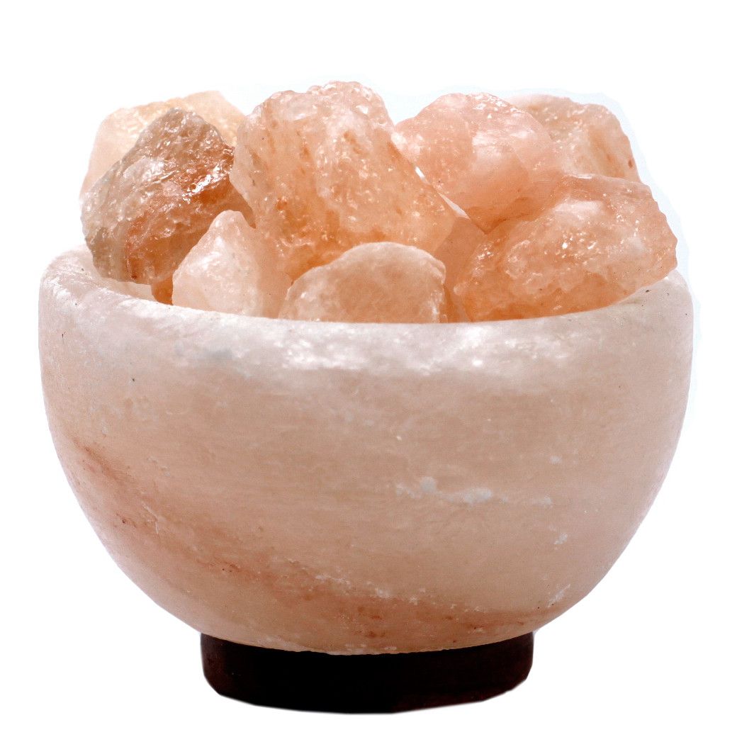 A decorative bowl carved from pink Himalayan salt filled with smaller raw salt chunks, emitting a warm orange glow.