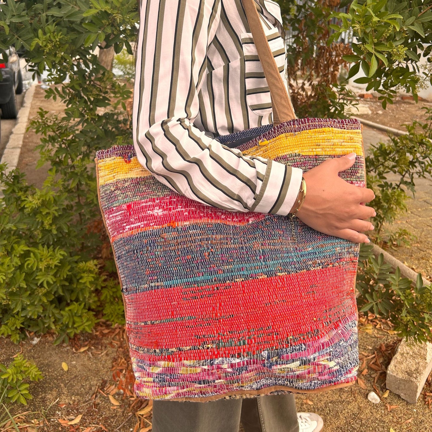 Large eco-friendly tote bag crafted from recycled rug materials in various vibrant shades of pink.