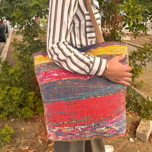 Large eco-friendly tote bag crafted from recycled rug materials in various vibrant shades of pink.