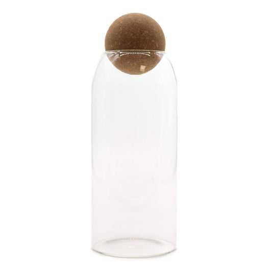 Tall clear glass storage jar with a round cork ball stopper sitting on the rim.