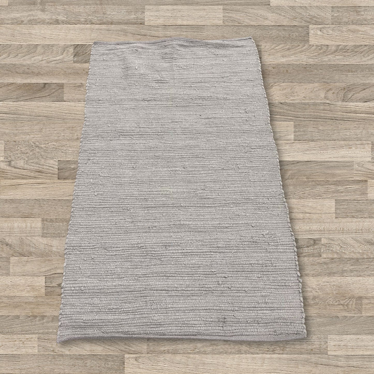 Handwoven small rectangular cotton rug in a soft grey shade with a subtle textured weave.