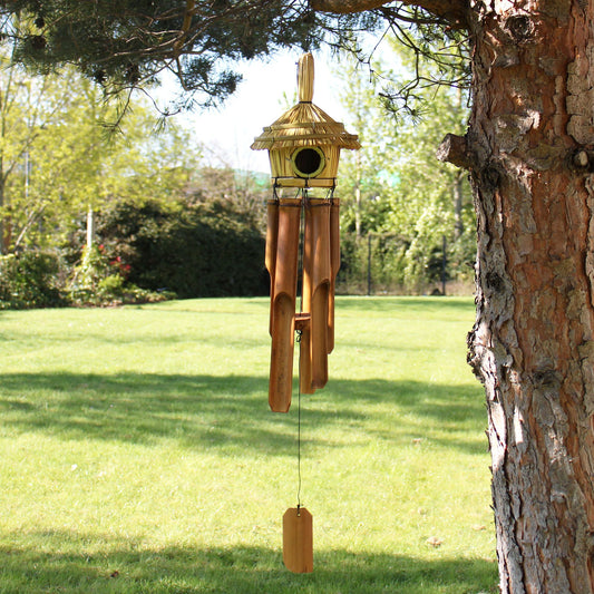 Round woven seagrass bird house with hanging metal chimes, featuring a natural rustic texture for garden decoration.