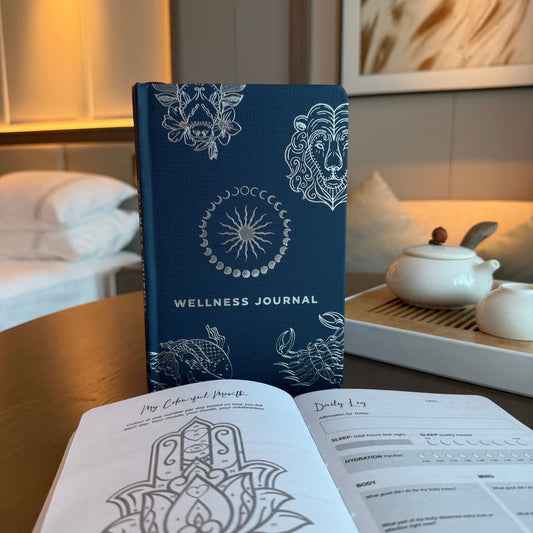 Midnight blue wellness journal with a shimmering silver zodiac and celestial star design on the front cover.