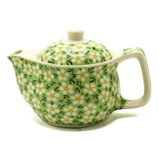 Small green ceramic teapot decorated with a delicate white daisy pattern and a whimsical design.
