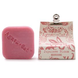 Round white solid shampoo bar with a textured floral surface on a natural wooden background.