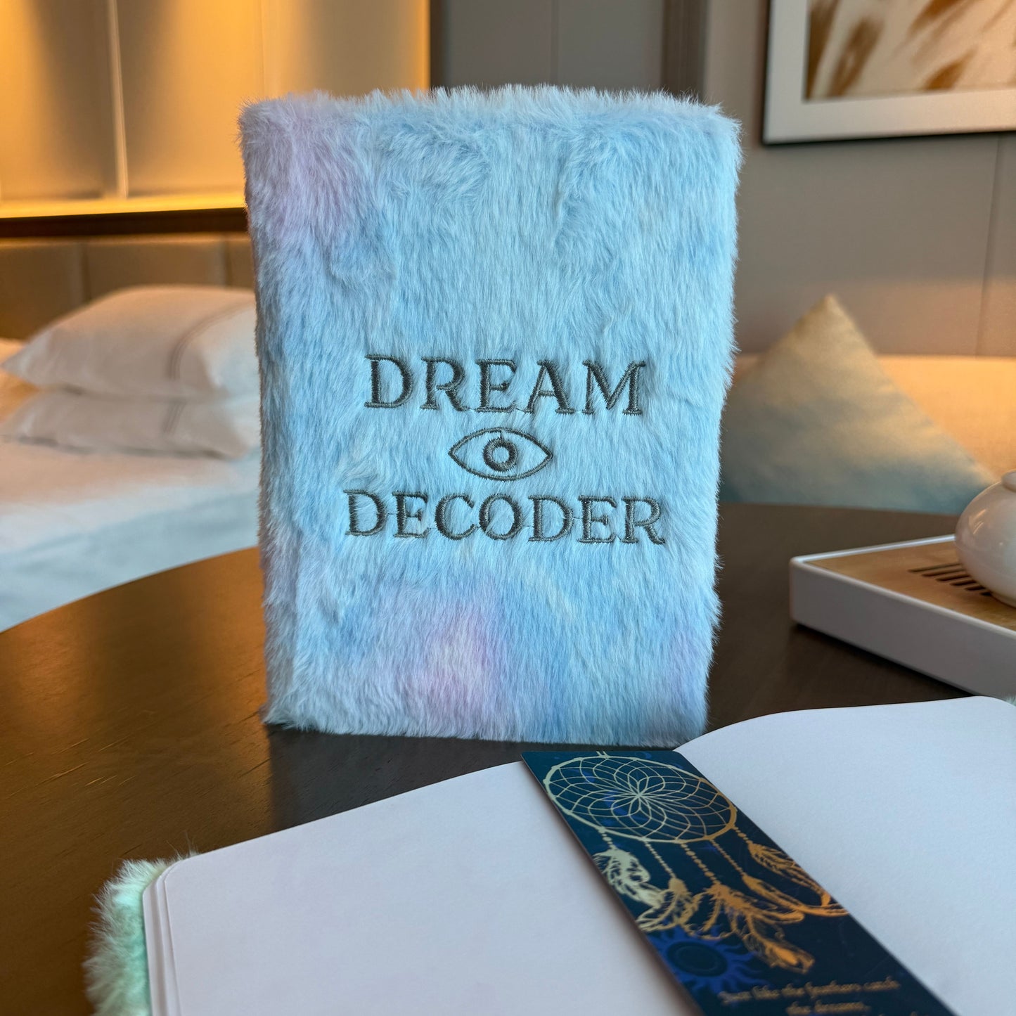 Soft pastel faux-fur dream journal featuring an embroidered all-seeing eye and silver Dream Decoder lettering.