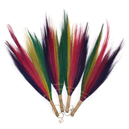Set of four natural pampas grass decorative brooms in vibrant rainbow colours hanging on a wall.