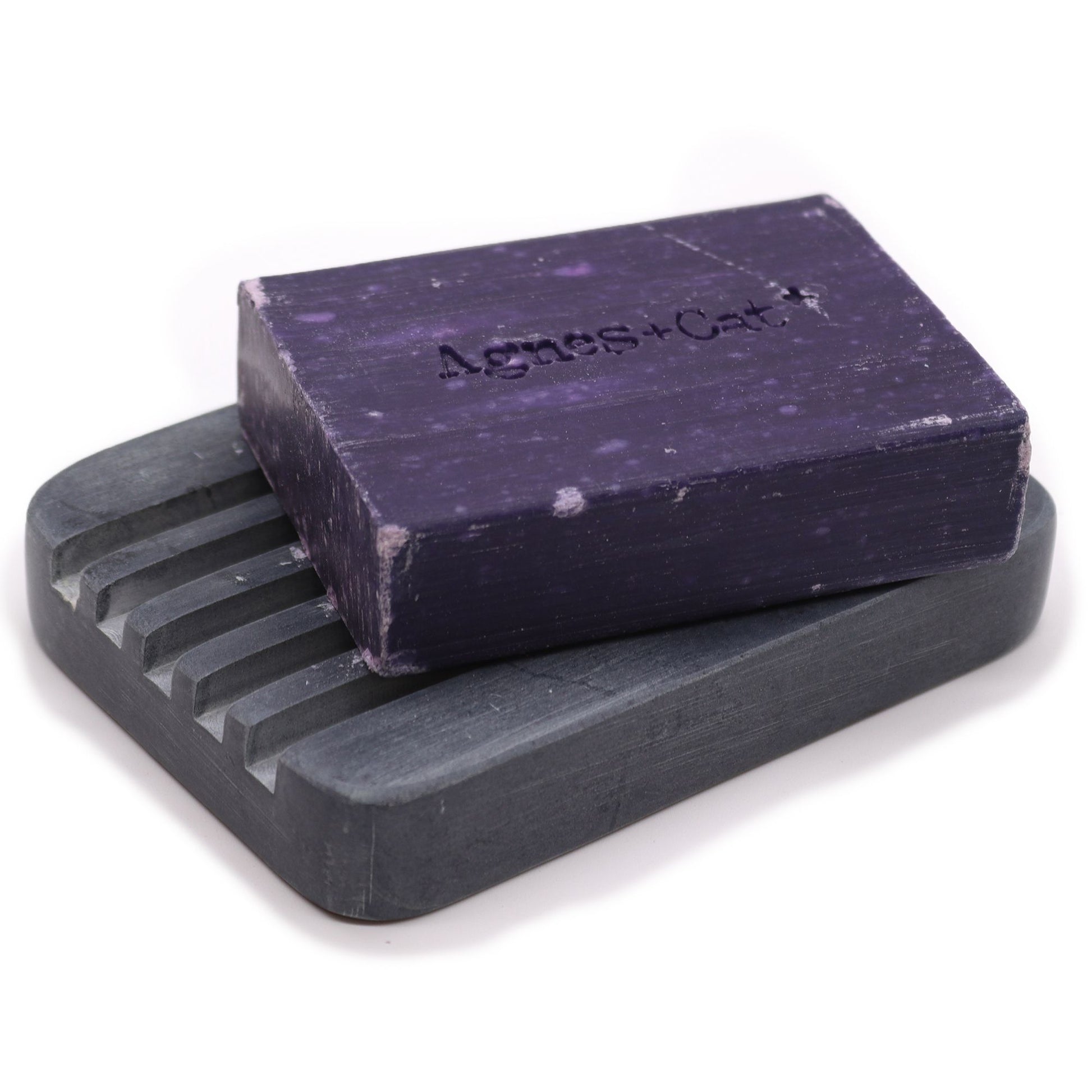 Hand-carved grey soapstone soap dish with deep parallel ridges and a natural stone finish.