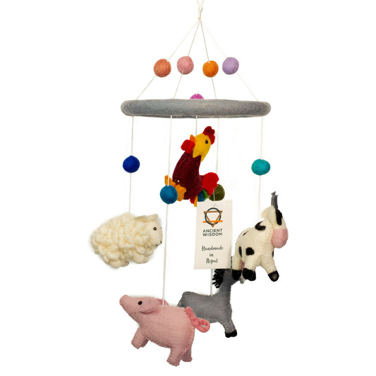 Handmade nursery mobile featuring colourful felt farm animals like a cow, sheep, and pig hanging from a wooden hoop.