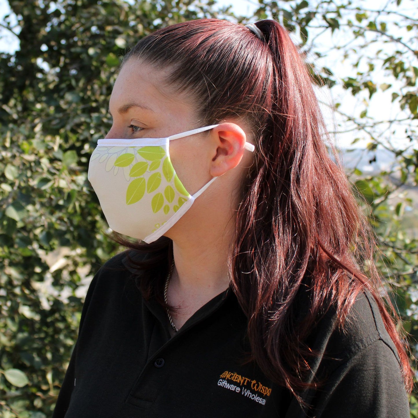 Adult-sized reusable fashion face covering featuring a vibrant green leaf pattern on a dark background.