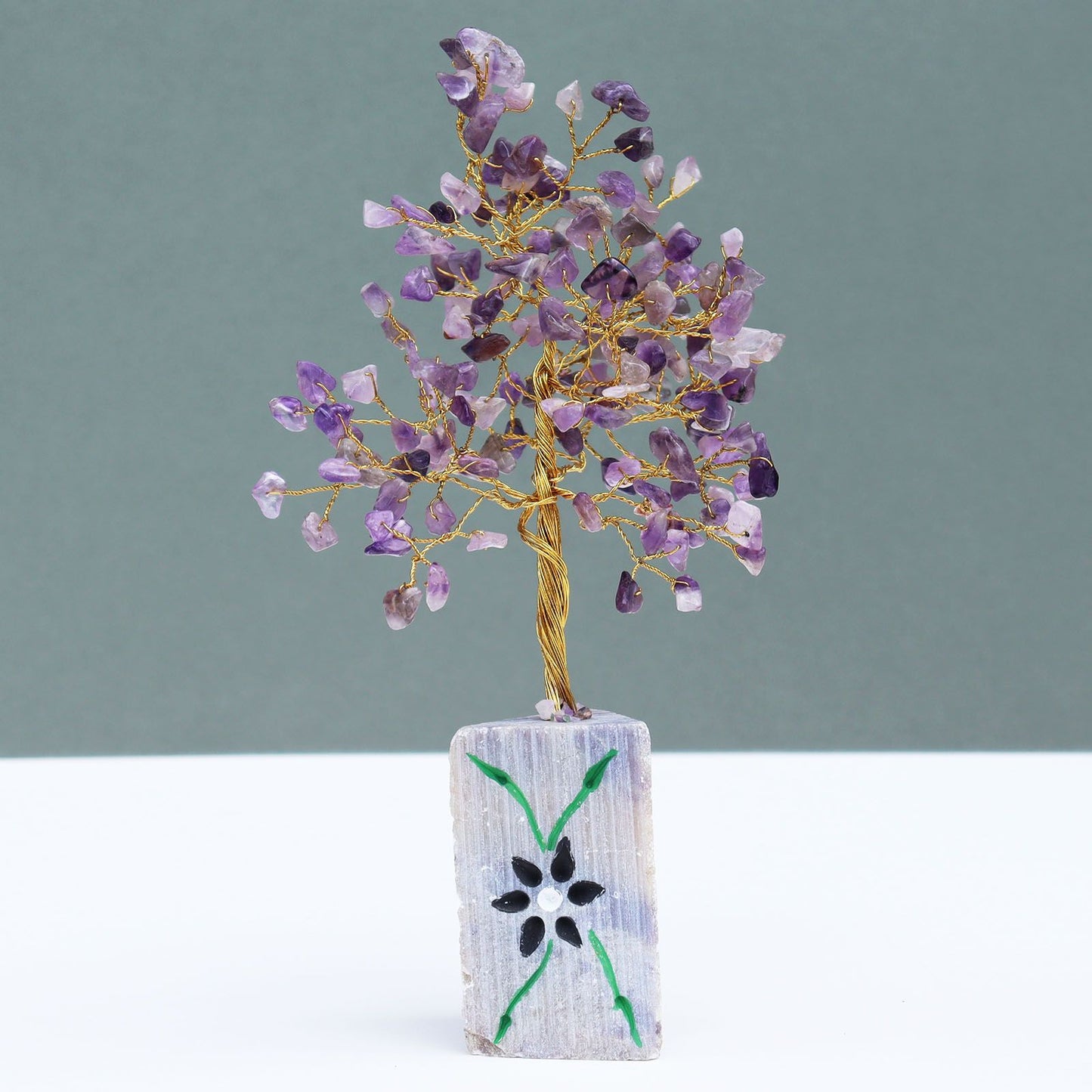 Handmade gemstone tree featuring purple amethyst crystal leaves on twisted wire branches set on a natural stone base.