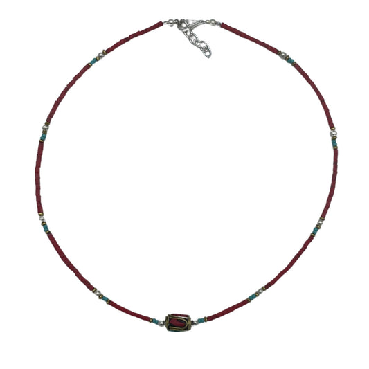 Handcrafted Nepalese necklace featuring vibrant red coral beads and intricate silver-tone tribal style accents.