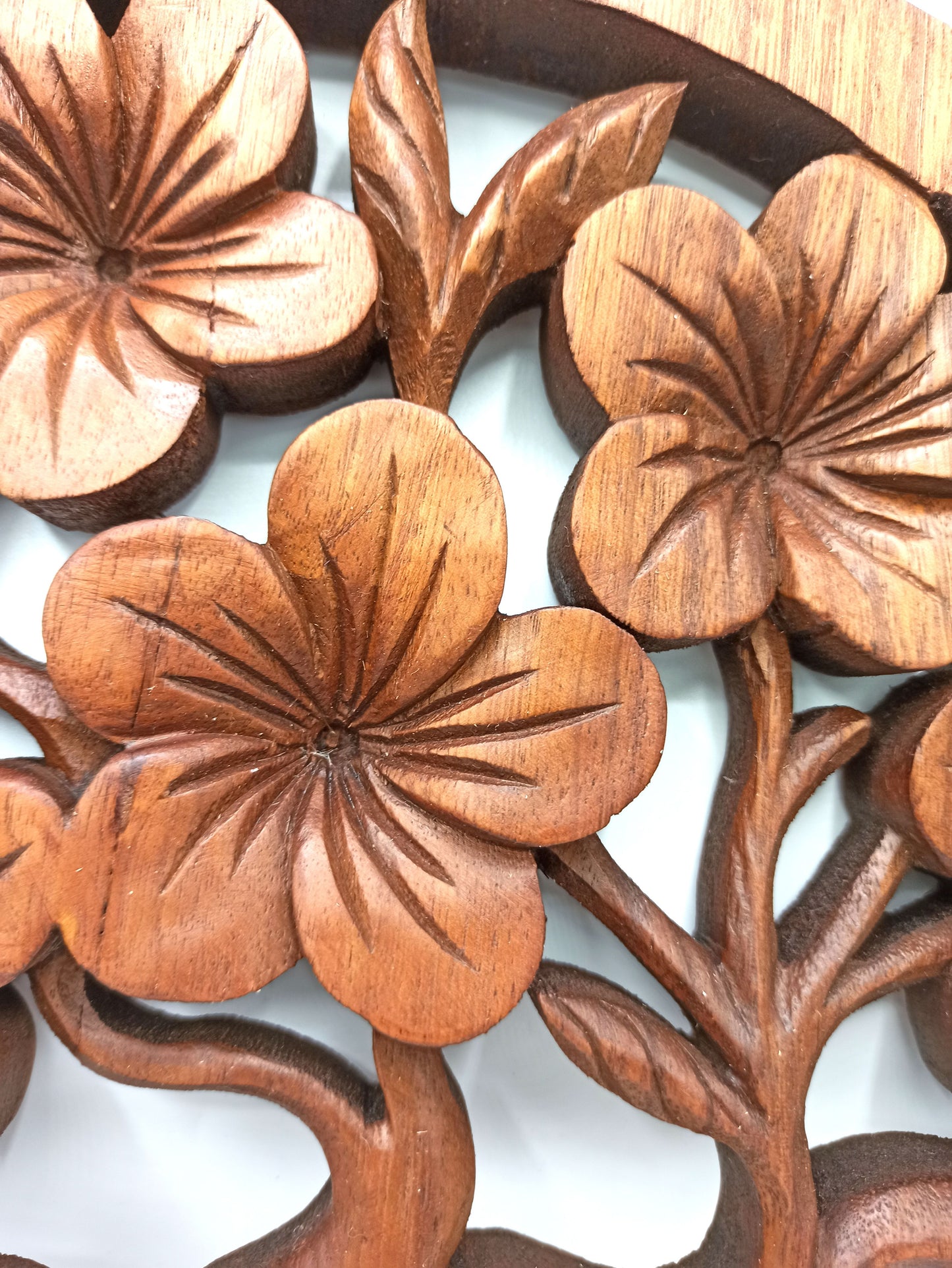 Circular hand-carved wooden wall panel featuring a Tree of Life design entwined with delicate frangipani flowers.